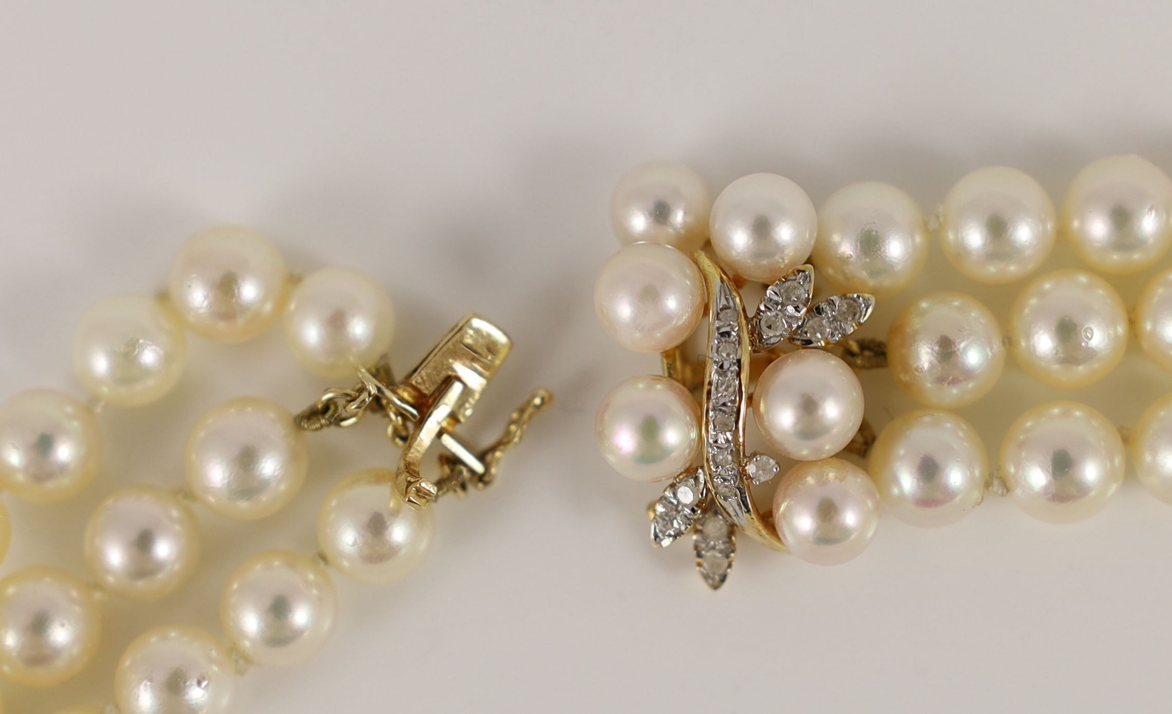 A modern triple strand cultured pearl necklace, with a 14k gold, cultured pearl and diamond set clasp